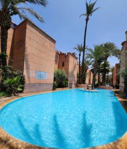 een groot blauw zwembad met palmbomen en een gebouw bij Quariya Assiyahiya Riad Camilia in Marrakesh