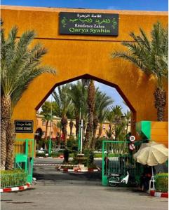 een toegang tot een gebouw met palmbomen en een bord bij Quariya Assiyahiya Riad Camilia in Marrakesh