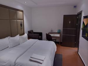 Una habitación de hotel con una cama blanca y un escritorio. en Hotel 35 Embassy, en Lagos
