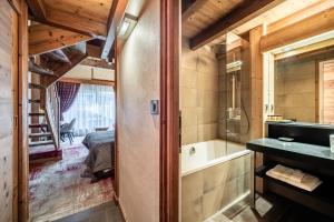 ein Bad mit einer Badewanne, einem Waschbecken und einem Bett in der Unterkunft Hotel Le Samoyede in Morzine