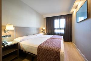 a hotel room with a bed and a television at Catalonia Park Güell in Barcelona