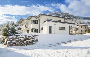 une maison blanche dans la neige avec une allée couverte de neige dans l'établissement 2 Bedroom Gorgeous Apartment In Wagrain, à Wagrain