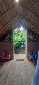 twee stoelen in een kamer met een veranda bij MALOCA - Chalés Rusticos in Ilha de Boipeba