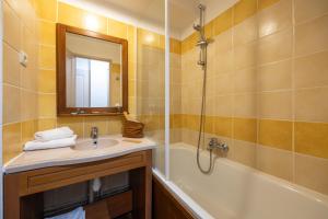 a bathroom with a sink and a tub and a mirror at Résidence Pierre & Vacances Les Trois Domaines in Ax-les-Thermes