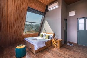 a bedroom with a bed with a large window at SaffronStays A Vantage, Panchgani - A Pyramid Shaped Unique Luxury Villa With Infinity Valley Views in Panchgani +9 photos