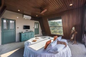 a bedroom with a large bed and a window at SaffronStays A Vantage, Panchgani in Panchgani