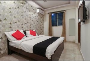 a bedroom with a bed with red pillows and a television at Hotel Golden inn in Bangalore
