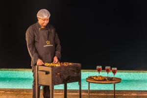 un hombre de pie junto a una mesa con copas de vino en SaffronStays A Vantage, Panchgani en Pānchgani