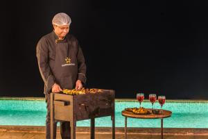 a man standing next to a table with wine glasses at SaffronStays A Vantage, Panchgani - A Pyramid Shaped Unique Luxury Villa With Infinity Valley Views in Panchgani