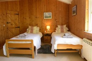 two beds in a room with wooden walls at Sawmill Cottage in Bridport