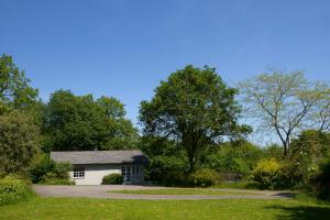 a small white house in the middle of a driveway at Sawmill Cottage in Bridport