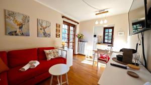 a living room with a red couch and a kitchen at Hostdomus - Edward Apartment in Cesana Torinese