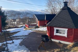 a red house with a grill on a wooden deck at Aurora House Dåfjord/Tromsø in Karlsøy