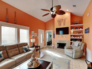 sala de estar con paredes de color naranja y ventilador de techo. en Mustang Isle Beach Bungalow #2, en Mustang Beach