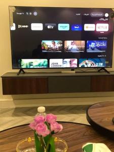 einen Tisch mit einer Vase mit einer Blume vor einem TV in der Unterkunft شقه فندقيه غرفه وصاله دخول ذاتى in Riad