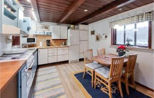 a kitchen with a wooden table and chairs and a kitchen with white appliances at 1 Bedroom Awesome Home In Ljungbyhed in Ljungbyhed