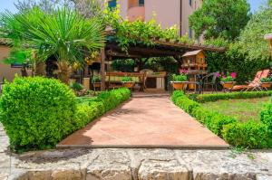 a garden with a stone walkway and a pergola with plants at Apartments Villa Amfora in Rovinj