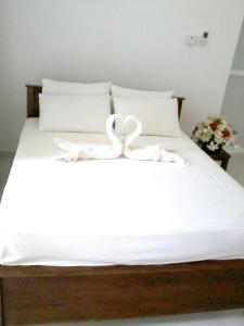 two swans sitting on top of a bed at Vintop Hotel & Homestays Gampaha in Gampaha