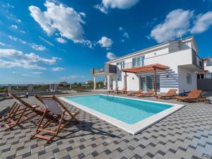 - une piscine avec des chaises et une maison dans l'établissement Stylish villa with private pool and terrace, à Sukošan