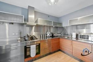 a large kitchen with wooden cabinets and stainless steel appliances at 2 bedroom duplex with wifi secure parking sleeps 8 in Nottingham