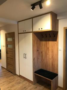 a locker room with white cabinets and a bench at Apartament Brązowy 12/1 in Starogard Gdański