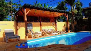a swimming pool with chairs and a gazebo at Jolie Villa Santa avec piscine in Pointe aux Piments