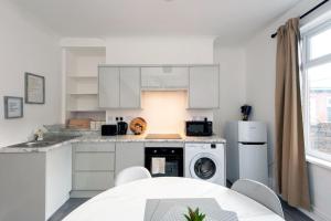 cocina con armarios blancos, lavadora y secadora en Prospect Terrace en New Brancepeth