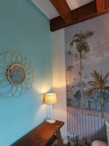a lamp on a table in a room with a painting at COTTAGE BLUE classé 3 étoiles - 4 à 6 personnes - 2 chambres - accès direct à la plage et à l'esplanade de Boucan Canot avec ses bars et restaurants in Saint-Gilles les Bains