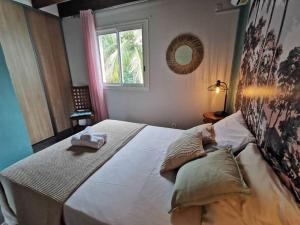 a bedroom with a large bed with two towels on it at COTTAGE BLUE classé 3 étoiles - 4 à 6 personnes - 2 chambres - accès direct à la plage et à l'esplanade de Boucan Canot avec ses bars et restaurants in Saint-Gilles les Bains