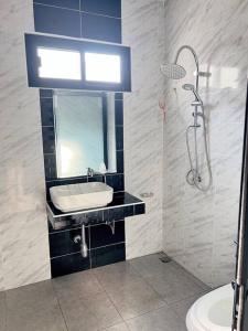 La salle de bains est pourvue d'un lavabo, d'un miroir et d'une douche. dans l'établissement Chaya Home&Hug Phrae, à Phrae
