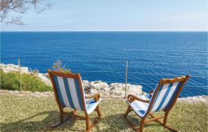 twee stoelen op het gras bij de oceaan bij Amazing Home In Porto Colom With House Sea View in Portocolom