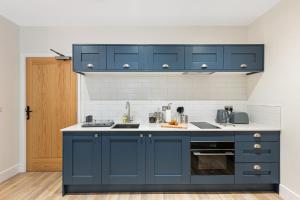 a kitchen with blue cabinets and a sink at Rock Mill Apartment 10 in Eyam
