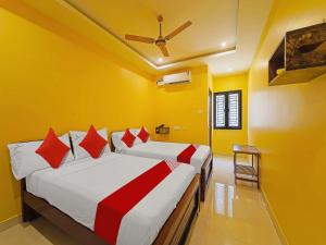 two beds in a room with yellow walls at OYO Flagship Jayam Residency in Tirupati