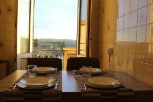 una mesa con platos y vasos con una ventana en Appartamento del Sol, Bilocale, en Varese
