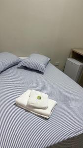 a bed with two towels sitting on top of it at Hotel Vila Rica in Maringá