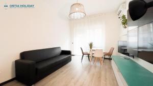 ein Wohnzimmer mit einem schwarzen Sofa und einem Tisch in der Unterkunft Appartamento Tramontana in Lido di Ostia