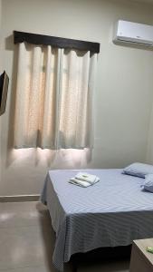 Cama en habitación con ventana y toallas en Hotel Vila Rica, en Maringá