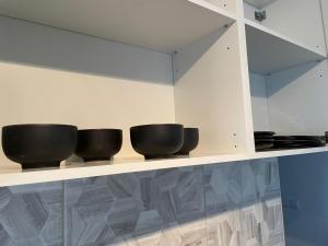 a row of black bowls sitting on a shelf at Balvi flat in Balvi