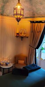1 dormitorio con cama, lámpara de araña y mesa en L'Aristoloche, en Salins-les-Bains