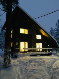 a house in the snow with the lights on at Ringo Cottage in Hakuba