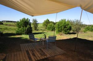 two chairs and a table under a tent at Monte dos Vagabundos - Animal Sanctuary - Caravan nest in São Teotónio