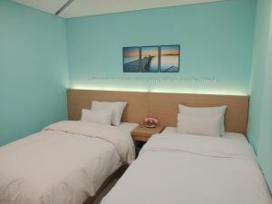 two beds in a room with a picture on the wall at Hotel Pop2 Jongno in Seoul