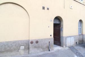 a building with two arches and a brown door at the house outside the walls in Siena