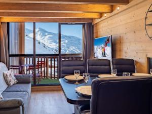 Una sala de estar con mesa y sillas y vista a la montaña. en Appartement montagne rénové, 6 pers, proche pistes et commodités - FR-1-637-59, en Val Thorens