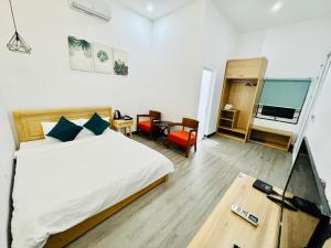 Schlafzimmer mit einem Bett und einem Tisch mit Fernbedienung in der Unterkunft D'Villa Hotel - Homestay in Kon Tum