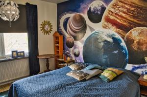 una camera da letto con un murale di pianeti e un letto di Bed and books på Österlens Gästhärbärge a Glemminge