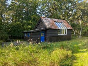 mały dom z niebieskimi drzwiami na polu w obiekcie Artist Studio w mieście Frederiksværk