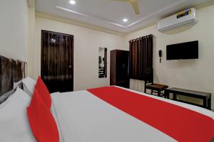 a bedroom with a red and white bed and a television at Hotel CJ Pride in Vijayawāda