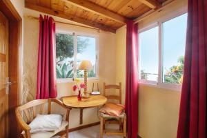 una mesa pequeña y sillas en una habitación con ventanas en Welcome in Paradise en La Matanza de Acentejo