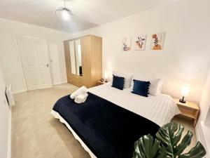 1 dormitorio con 1 cama grande con almohadas azules en Spacious 3-bed top-floor flat w/ balcony, en Borehamwood